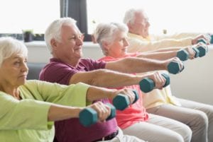 A group of older people holding dumbbells in a row.